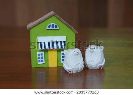 front view two white and red wooden polar bear figures and a green and white wooden house placed on a wooden floor, wall wooden background, nature, object, decor, fashion, copy space                                                