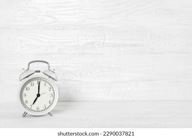 Front view white desk with alarm clock, coffee mug and copy space. Morning background banner with free space for text. Minimalistic concept, workspace, time to work. Blank workplace. Office mock-up.