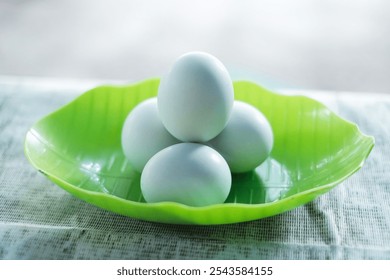 Front view of white salted eggs in a stack of bowls shaped like green leaves.