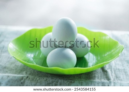Front view of white salted eggs in a stack of bowls shaped like green leaves.