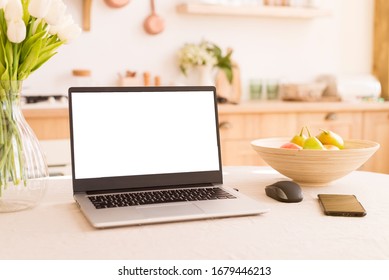 Front view of white screen laptop in kitchen with soft and warm light. Remote work. freelance. flowers and fruits on the table. Work from home. Telework. Copy space