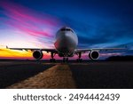 Front view of the wide body passenger aircraft at the airport apron against the backdrop of a scenic sunset sky