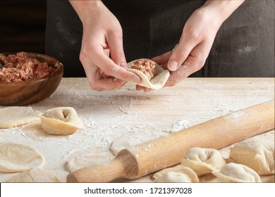 Front view of woman's hands making meat dumpling with wooden rolling pin.  - Powered by Shutterstock