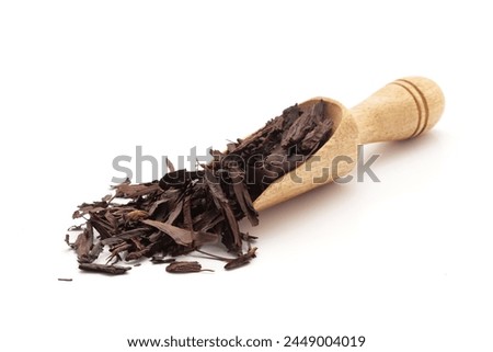 Front view of a wooden scoop filled with Organic Alkanet or Ratan Jot (Alkanna tinctoria) roots. Isolated on a white background.