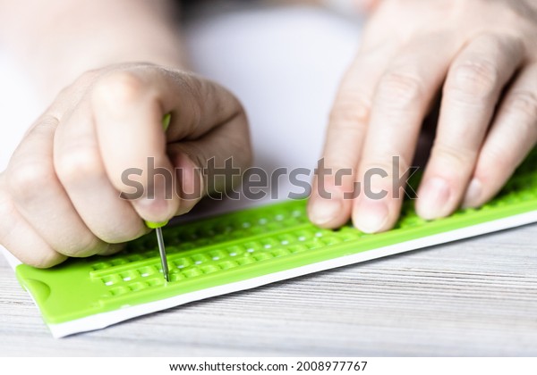 front view of writing in braille with slate and stylus\
close up