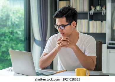 Front View Young Asian Man Working From Home Looking At The Laptop.