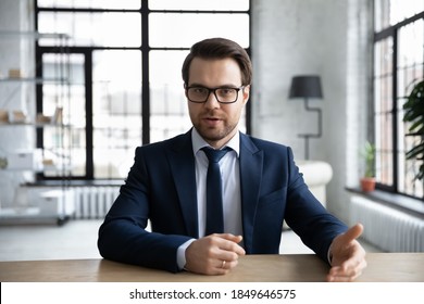 Front view young male executive manager in formal wear holding negotiations meeting with colleagues, discussing working issues or giving professional consultation to clients online in modern office.