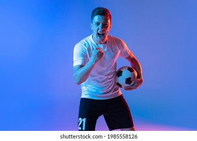 Front view of young man, professional football player standing isolated on gradient blue pink background in neon light. Concept of facial expressions, team game, energy, sport. Bright emotions - Powered by Shutterstock