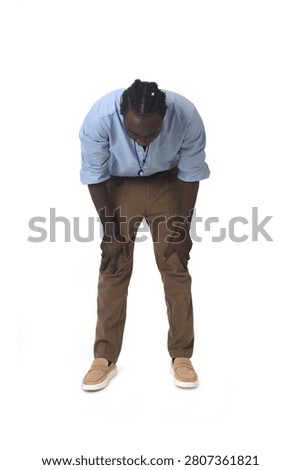 front view of a young man standing hunched looking down on a white background