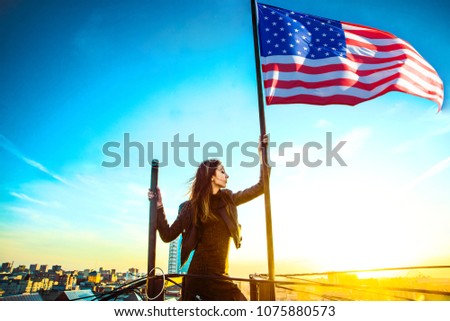 front view of young woman looking at american flag on top of the roof. Independence day 4th of July -  independence day.