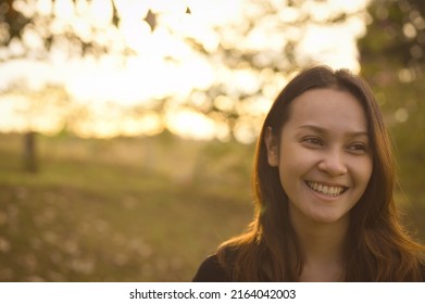 Front view of young woman warm smile with bokeh in golden hour