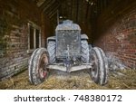  The front of a vintage tractor in an old brick barn with straw floor                             