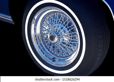 The Front Wheel Of A Car Complete With White Wall Tire And Spoked Rim.