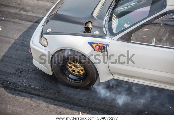 Front wheel drive sport car burning tire for\
warm up before competition start to increase type temperature for\
good traction.