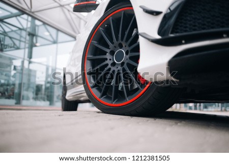 Front wheel of modern sportcat. Black rims on the white supercar