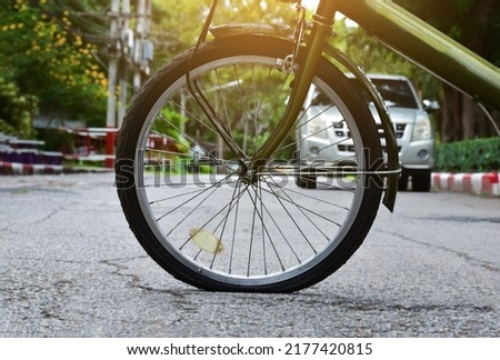 Front wheel or front tire of mini bike which is flat during cycling in the public park, soft and selective focus.