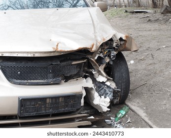 The front of a white car lays in ruins, the metal twisted and smashed from a recent collision. The once sleek design is now marred by dents and broken pieces