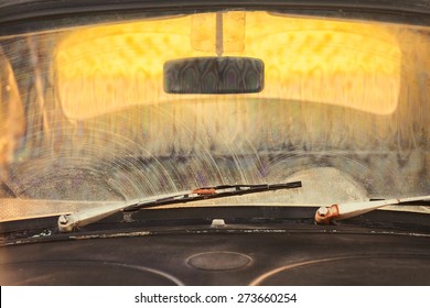 Front Window Of A Dirty Old Black Car With Rusted Screen Wipers