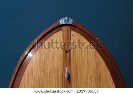 The front of a wooden boat on a blue background top view. Expensive wooden lacquered part of the boat. Fore deck. Wooden deck on a blue background top view.