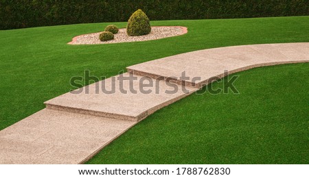 Front yard with garden path and outside staircase made of granite and artificial turf