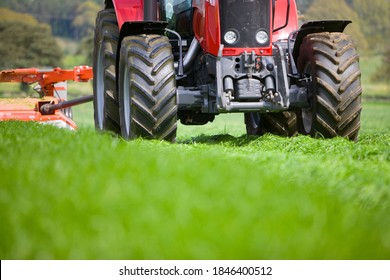 A Frontal Closeup Up Of A Tractor Pulling The Chopper On A Farm Field While Cutting The Green Grass For Silage.