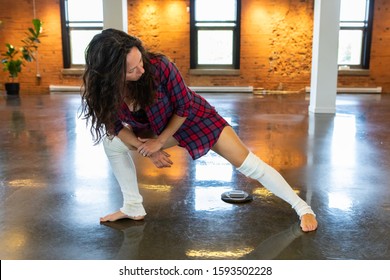 A Frontal Full Body View Of An Empowered Woman Performing Leg Warmup Stretches, Preparing For A Yoga Session In The Gym, With Copy Space On The Left