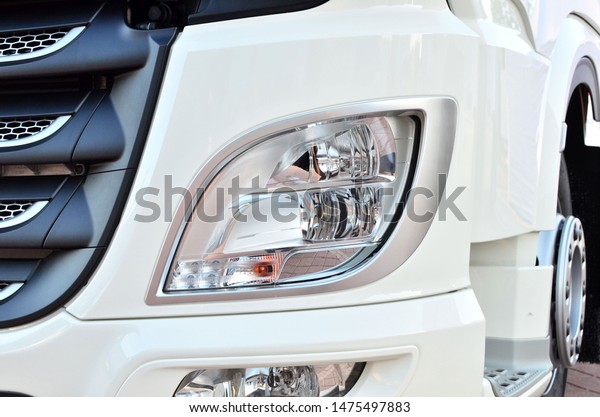 Frontal lighting products for on-highway vehicles,\
which includes integrated daytime running lights and beam patterns.\
Bi-Xenon and halogen headlamp of a modern truck, background texture\
- Image