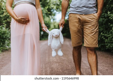 frontal mid section photo of pregnant wife and her husband carrying a stuffed animal - Powered by Shutterstock