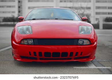 A frontal photo of an red Italian sport car from the 90s