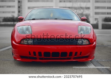 A frontal photo of an red Italian sport car from the 90s