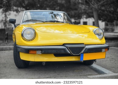 A frontal photo of a yellow Italian roadster on display with selective color 