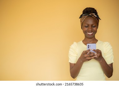 frontal portrait of a young woman smilling while typing on her smartphone  - Shutterstock ID 2165738635