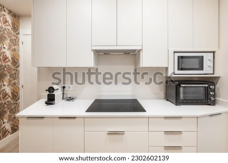 Frontal shot of a white kitchen unit with functional appliances and a convection hob. The concept of convenience and simplicity in interior design for young families