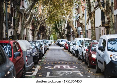 Frontal View Of A City Street With Cars Parked On Both Sides