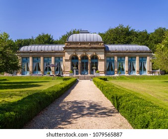 Frontal View Of An Early Nineteenth Century Conservatory Or Orangery With Big Windows And A Symmetrical Garden In Front