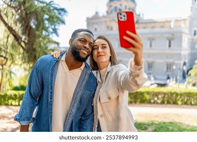 Frontal view of a happy multi-ethnic couple embraced taking selfie in city viewpoint - Powered by Shutterstock