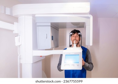 Frontal view of a male patient with eyes closed in a dental x-ray machine - Powered by Shutterstock