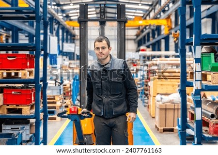 Frontal view of a male worker walking among shelves with handcart in a warehouse