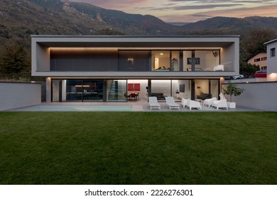 Frontal view modern house with swimming pool and garden illuminated by LED lights at sunset. Nobody inside - Powered by Shutterstock