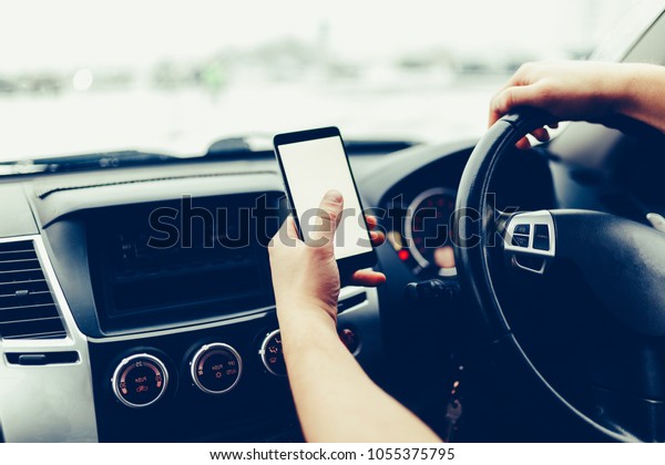 Frontal view of modern smartphone with blank screen\
with copy space for text or design, close-up male driver hands\
using mobile phone in luxury car. Phone\'s touch screen, GPS\
navigation. Toned photo