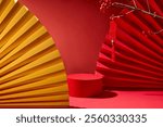 A frontal view of a red podium with space for display products, red and yellow handmade paper fans, and a winterberry branch hanging a lucky string. Template picture with Asian New Year concept.