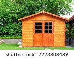 Frontal view of wooden garden shed glased in teak color