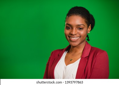 A front-view portrait shot of a young africian woman standing in front of a green screen, she is smiling and looking at the camera. - Powered by Shutterstock