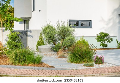 The frontyard of a modern house, garden details with colorful plants, dry grass beds surrounded by grey rocks. - Shutterstock ID 2350432163