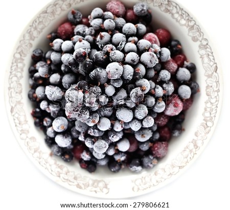 Frosen cranberries and black currant berries in white bowl isolated