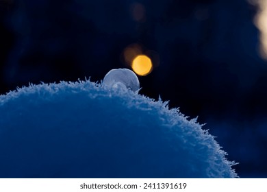 frosen soap bubble on top of snow  sun in the bacground winter time 