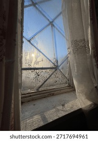 Frost patterns on the window of an old house through which the sun shines