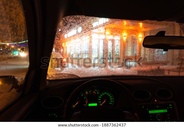 frosted car glass. snow covered car
windshield. view from inside the car on the night
city