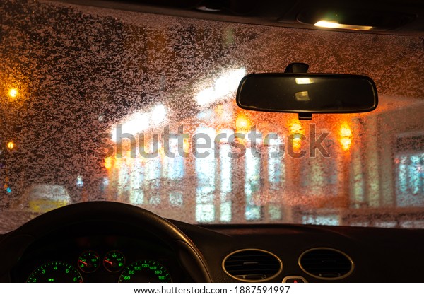 frosted car glass. snow covered car\
windshield. view from inside the car on the night\
city