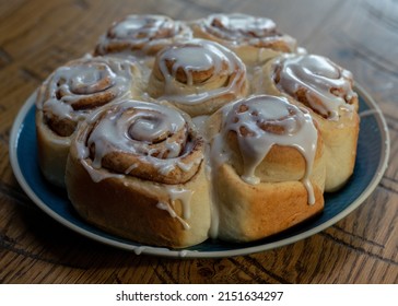 Frosted Cinnamon Rolls On Blue Plate, Wooden Counter Top